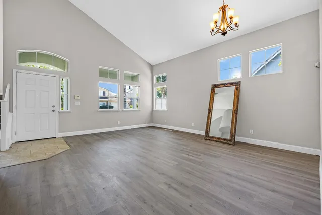 an empty room with windows and chandelier fan
