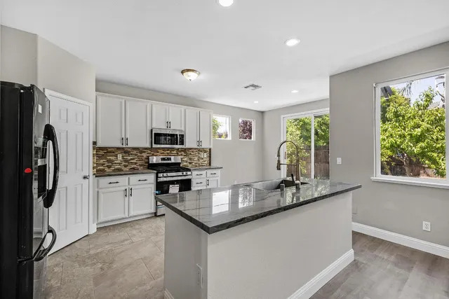 a kitchen with granite countertop stainless steel appliances a refrigerator sink and microwave