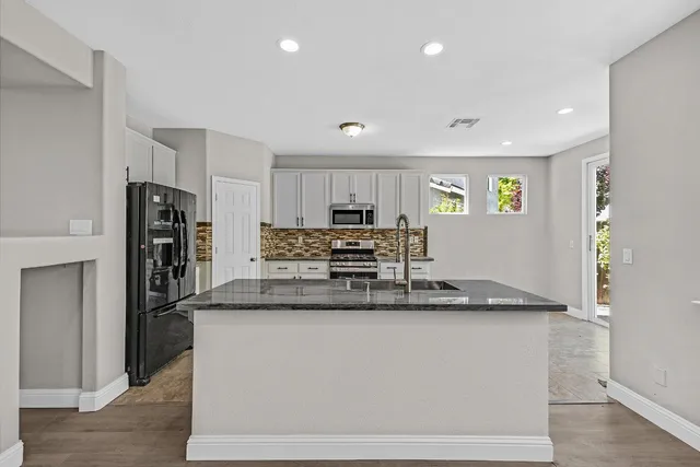 a large kitchen with stainless steel appliances granite countertop a refrigerator and a stove