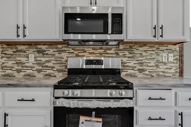 a kitchen with stainless steel appliances granite countertop a stove and a microwave