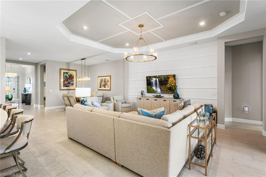 15216 Turin Drive Naples, FL 34114 - Photo 12 of 50 Living area featuring suspended lighting, a tray ceiling, and light wood-style floors