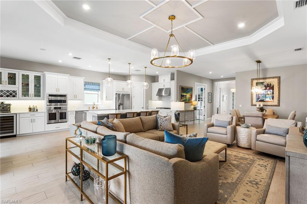 15216 Turin Drive Naples, FL 34114 - Photo 13 of 50 Living area with hanging lights, wine cooler, light wood-style flooring, and a tray ceiling