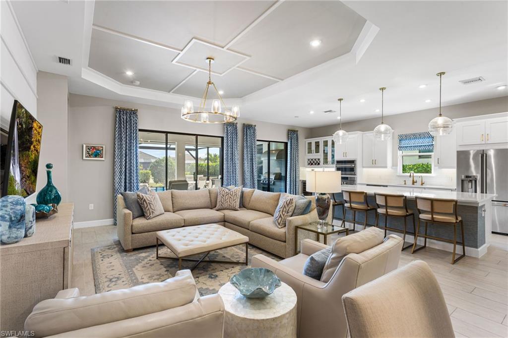 15216 Turin Drive Naples, FL 34114 - Photo 14 of 50 Living room with hanging lights, plenty of natural light, a raised ceiling, and light wood-style floors