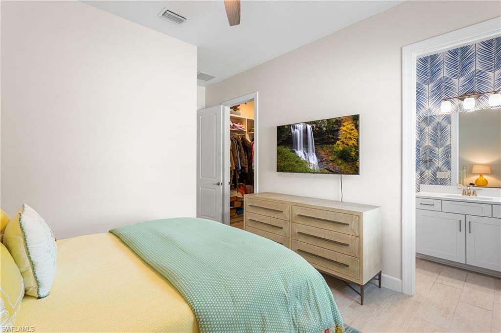 15216 Turin Drive Naples, FL 34114 - Photo 24 of 50 Bedroom featuring a spacious closet, a ceiling fan, and ensuite bath