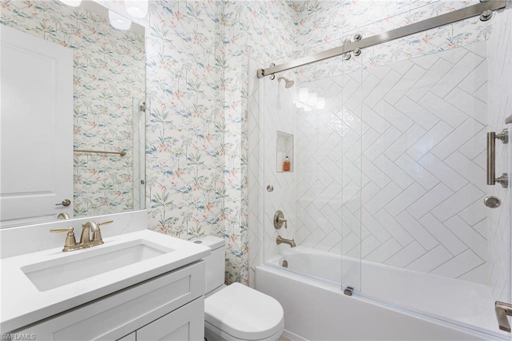 15216 Turin Drive Naples, FL 34114 - Photo 29 of 50 Full bath featuring wallpapered walls, combined bath / shower with glass door, and vanity