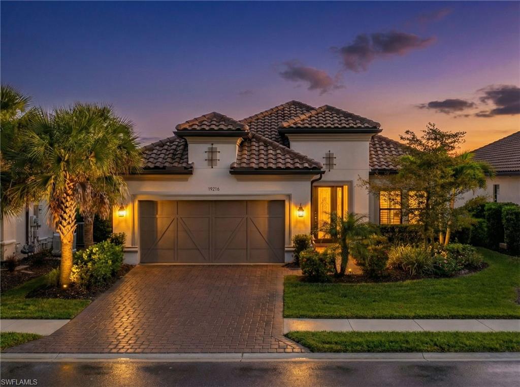 15216 Turin Drive Naples, FL 34114 - Photo 6 of 50 Mediterranean / spanish-style home featuring decorative driveway, an attached garage, stucco siding, a tile roof, and a front yard
