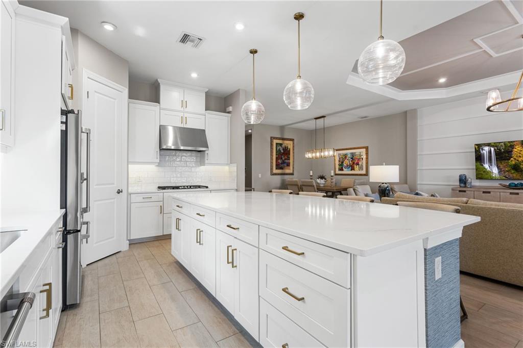 15216 Turin Drive Naples, FL 34114 - Photo 50 of 50 Kitchen featuring a center island, open floor plan, white cabinets, light stone countertops, and suspended lighting