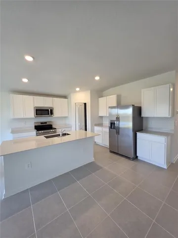 a large kitchen with stainless steel appliances a large counter top a stove and a refrigerator