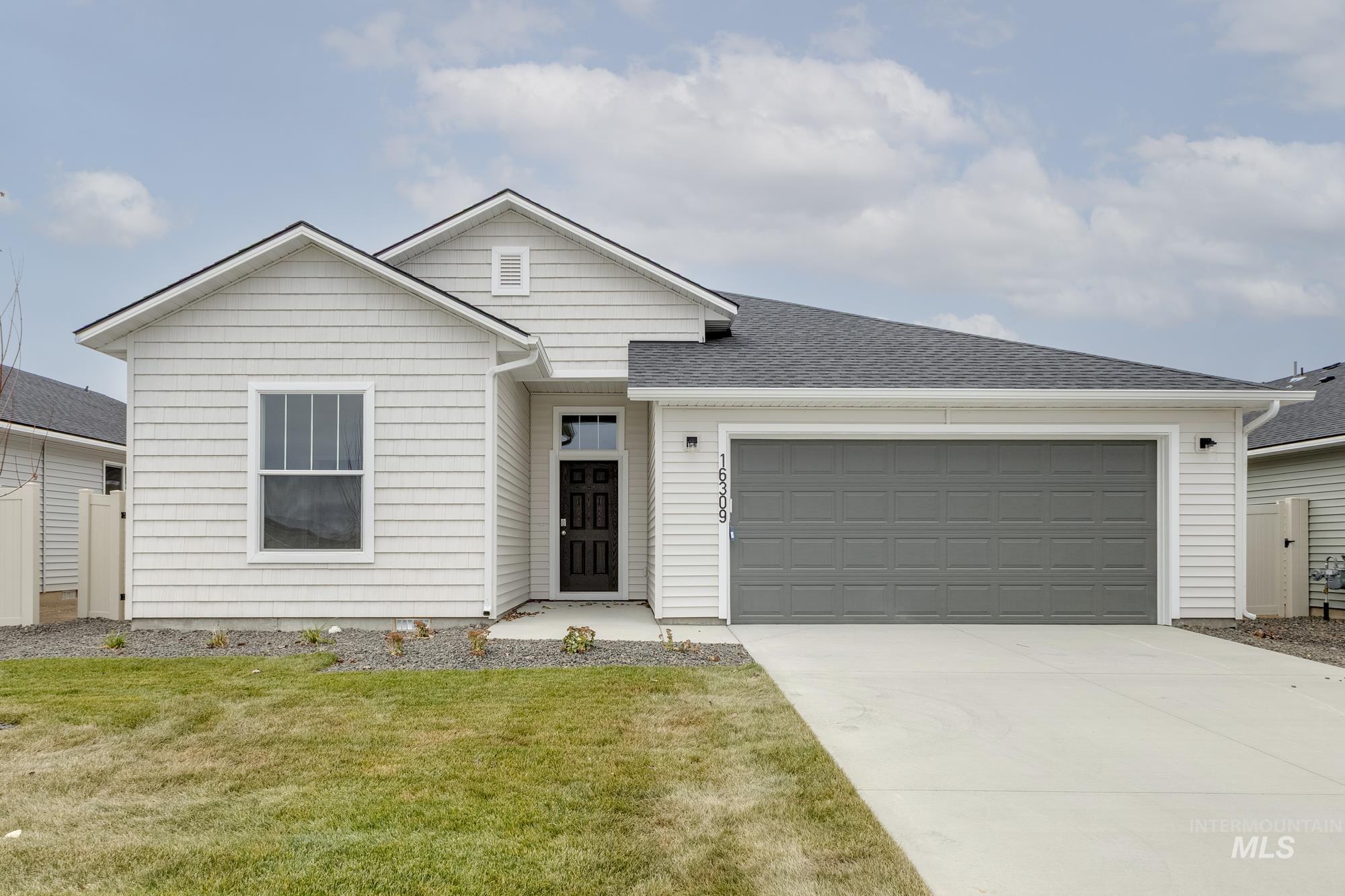 Single story home featuring driveway, an attached garage, and roof with shingles