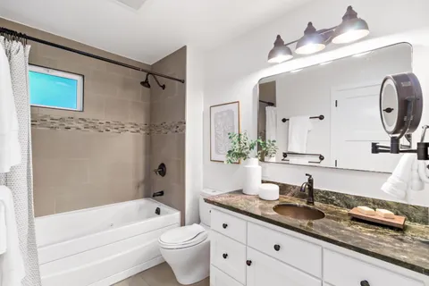 a bathroom with a granite countertop sink mirror toilet and bathtub