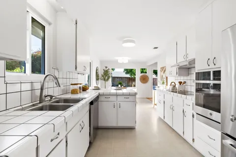 a kitchen that has a lot of white cabinets and stainless steel appliances