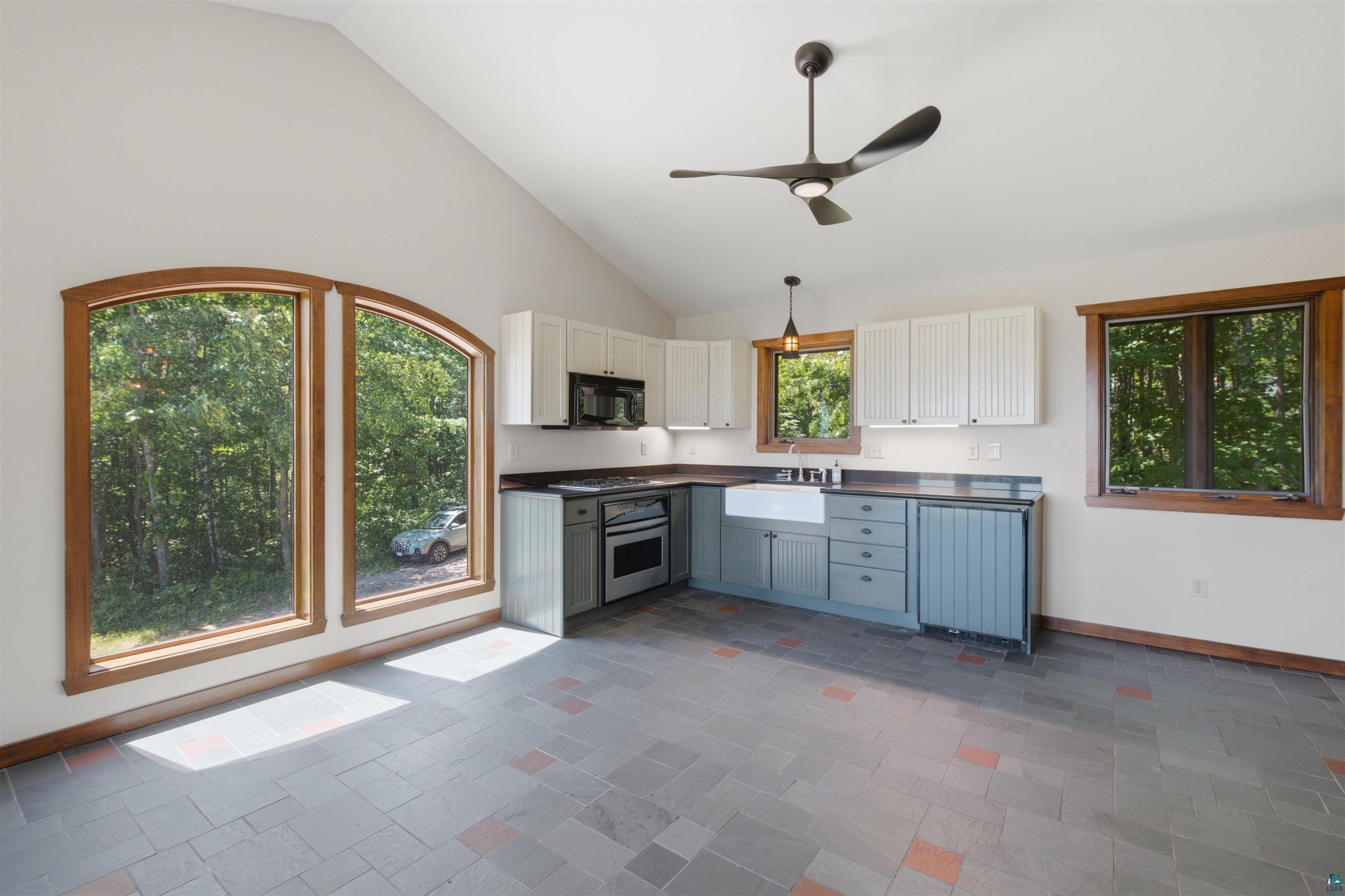 86270 Meyers-Olson Road Bayfield, WI 54814 - Photo 15 of 33 Kitchen featuring vaulted ceilings, a contemporary ceiling fan, and large arched windows with wood trim