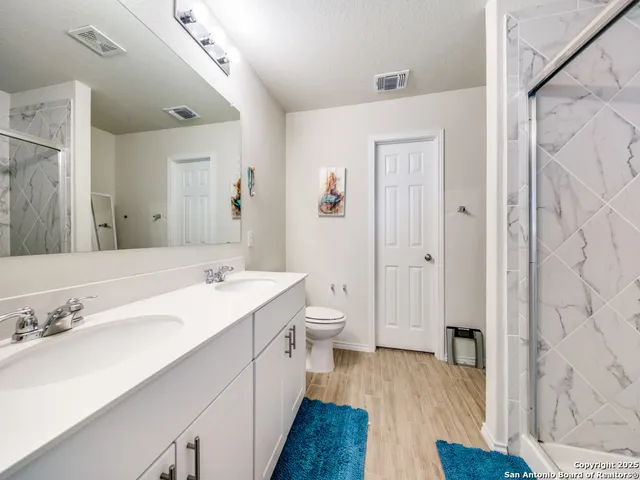 a spacious bathroom with a double vanity sink a mirror and a shower