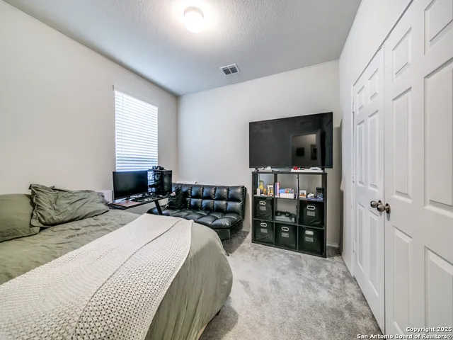 a bedroom with a bed and a flat tv screen on the dresser