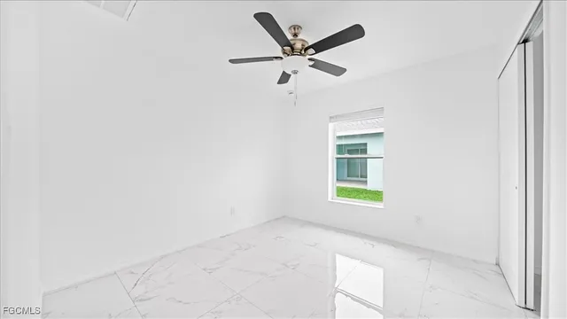 an empty room with a window and a fan