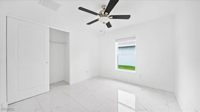 an empty room with a window and a ceiling fan
