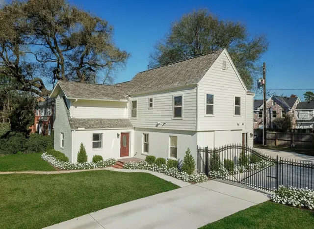 a view of a white house next to a yard with big trees
