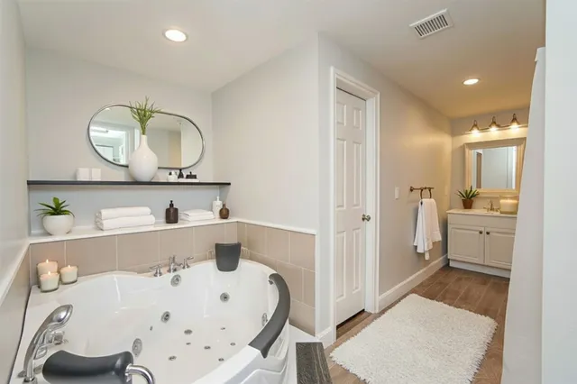 a spacious bedroom with a bed a chandelier and a mirror