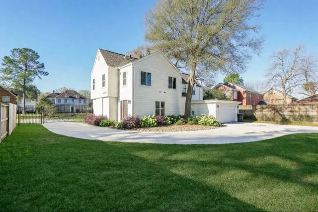 a view of a white house with a big yard and large tree