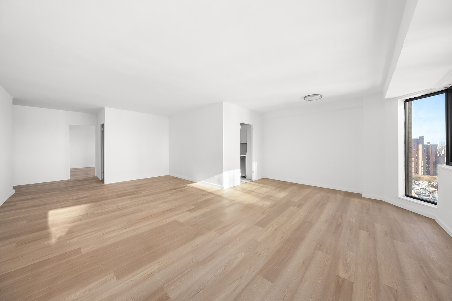 1725 York Avenue, Unit 31H Manhattan, NY 10128 - Photo 2 of 11 a view of an empty room with wooden floor and a window