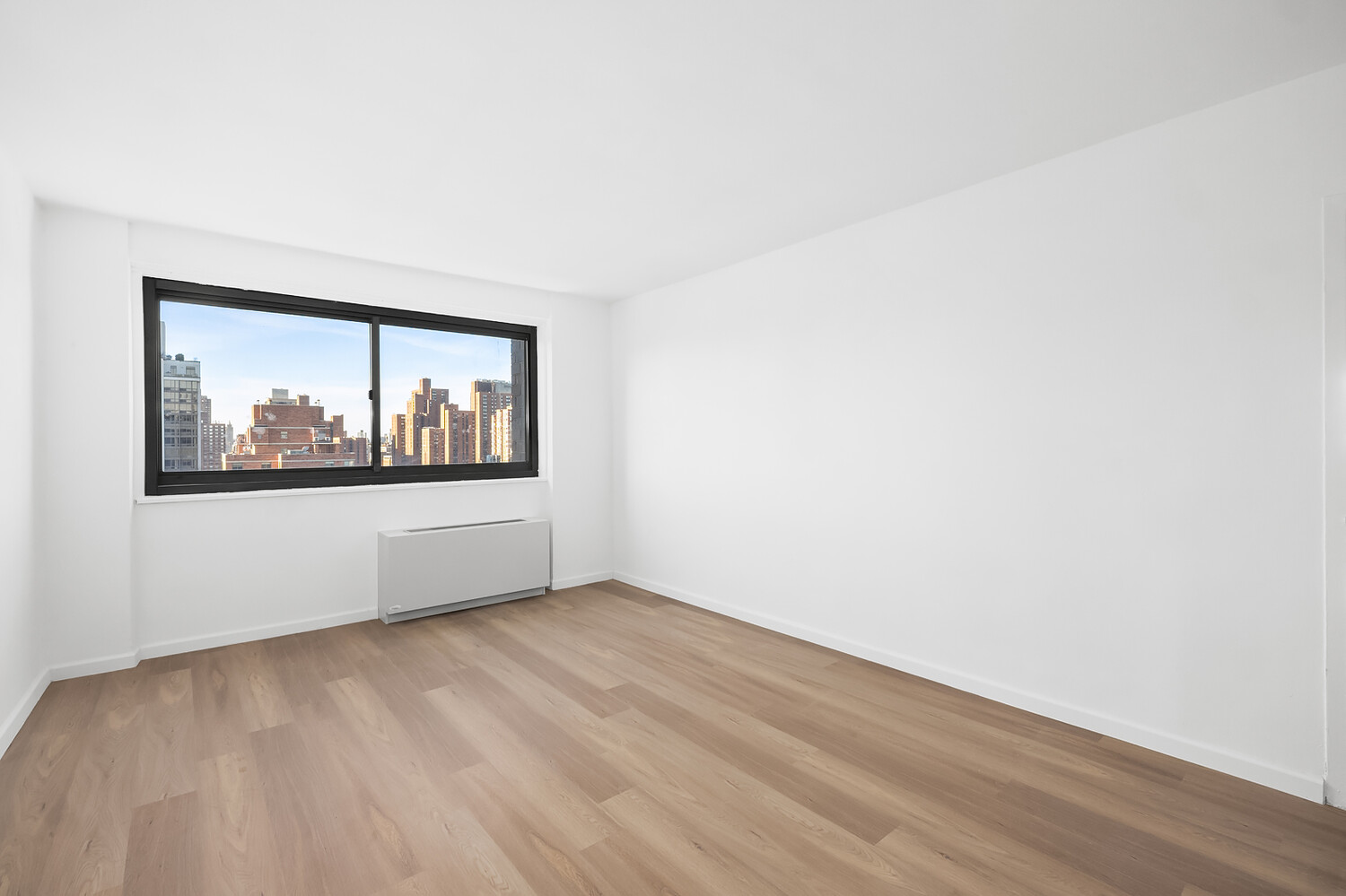 1725 York Avenue, Unit 31H Manhattan, NY 10128 - Photo 7 of 11 a view of empty room with wooden floor and fan