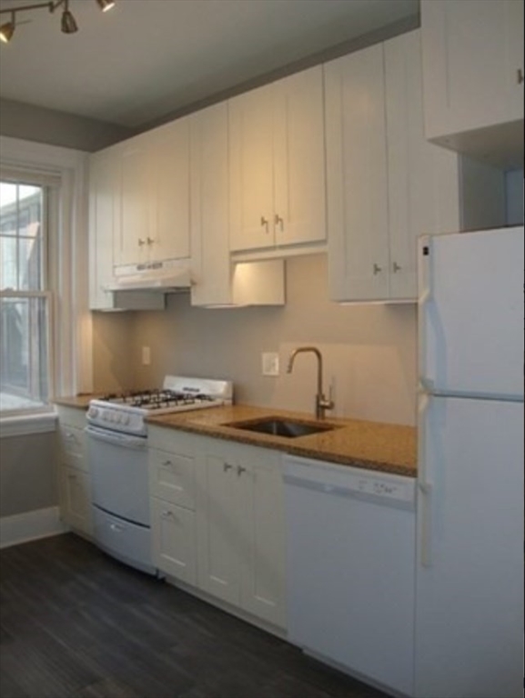 25 Mt Hood Road, Unit 12 Boston, MA 02135 - Photo 6 of 8 a kitchen with granite countertop a sink and a stove top oven