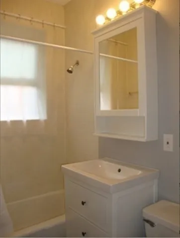 a bathroom with a granite countertop sink a toilet and shower