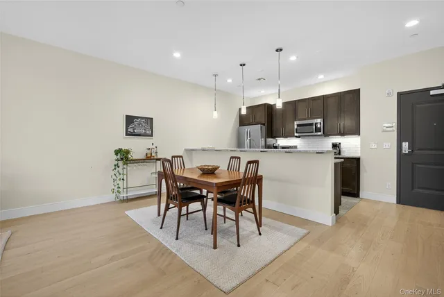 a kitchen with kitchen island a dining table chairs and refrigerator