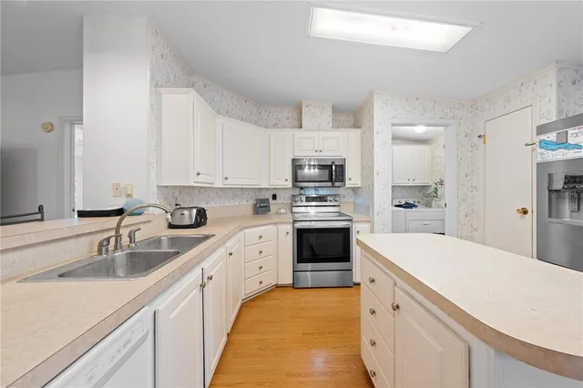 a large white kitchen with cabinets a sink a stove a refrigerator and cabinets