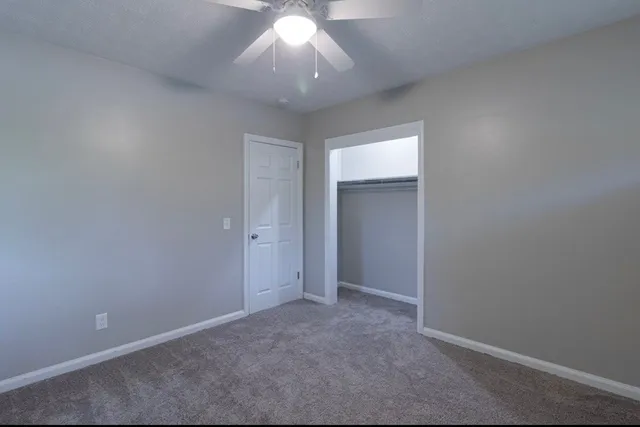 an empty room with a ceiling fan and a window