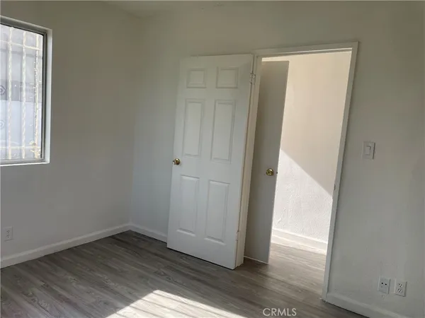 an empty room with wooden floor closet and windows