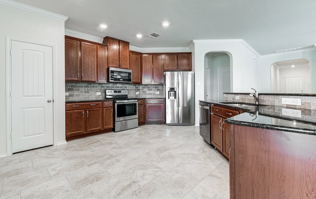 1237 Volente Lane Leander, TX 78641 - Photo 6 of 22 Culinary dreams come alive in this kitchen, boasting dark wood cabinetry and polished granite countertops.
