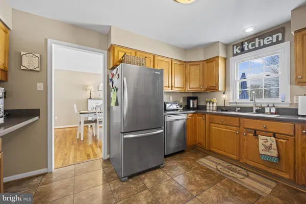 a kitchen with granite countertop a refrigerator a sink a stove top oven and cabinets