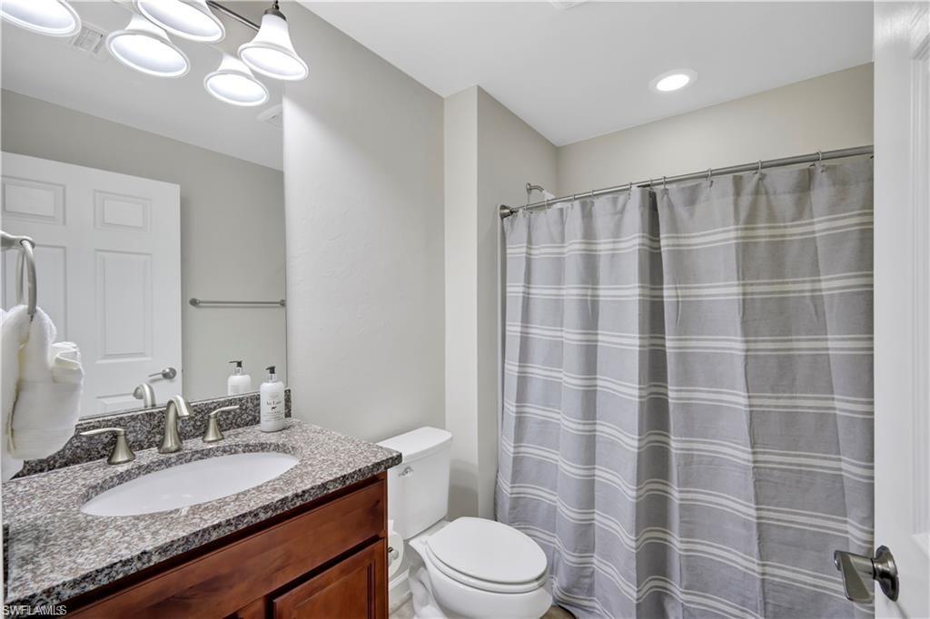 7103 Lily Way Naples, FL 34114 - Photo 24 of 41 a bathroom with a granite countertop sink a toilet a mirror and shower