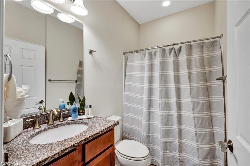 7103 Lily Way Naples, FL 34114 - Photo 27 of 41 a bathroom with a granite countertop sink a toilet a mirror and shower
