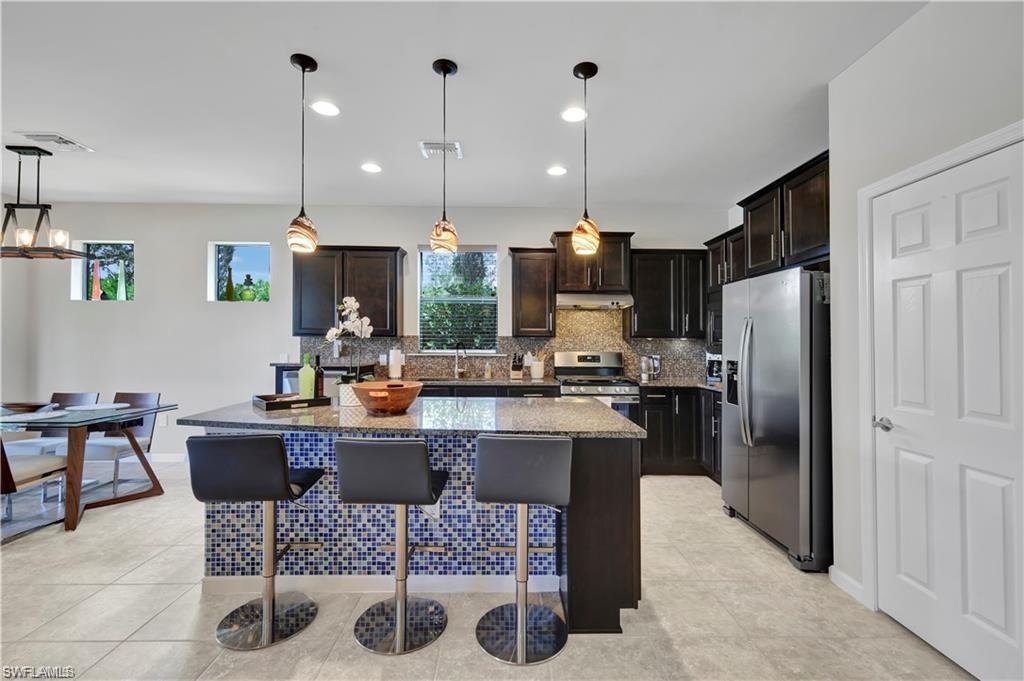 7103 Lily Way Naples, FL 34114 - Photo 4 of 41 a kitchen with refrigerator and chairs
