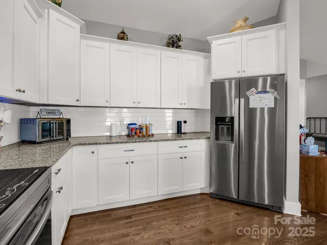 a kitchen with granite countertop white cabinets and stainless steel appliances