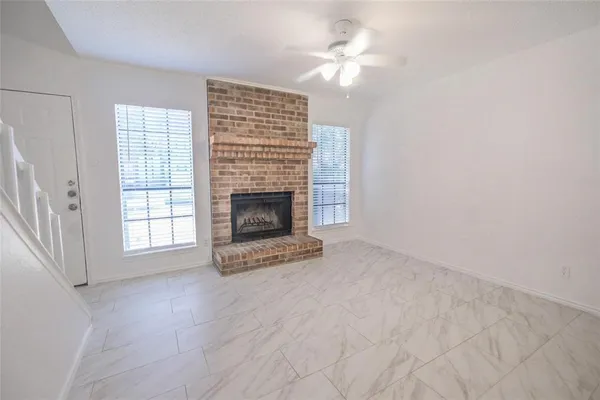 an empty room with windows and fireplace