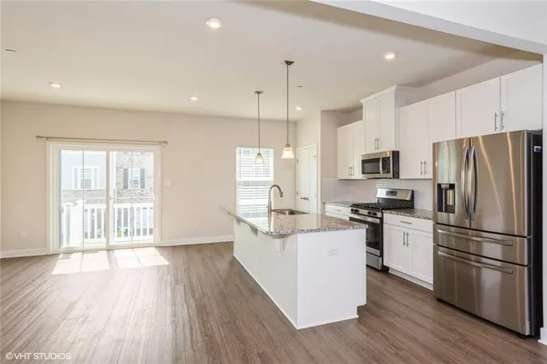 a kitchen with stainless steel appliances granite countertop a refrigerator a stove top oven a sink dishwasher and a refrigerator with wooden floor