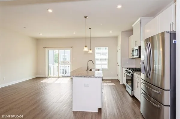 a kitchen with stainless steel appliances granite countertop a refrigerator a stove and a wooden floors