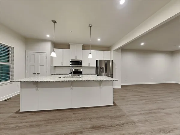 a large kitchen with stainless steel appliances a large counter top a stove a refrigerator and a microwave