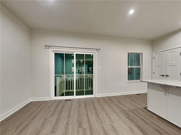 a view of an empty room with wooden floor and windows