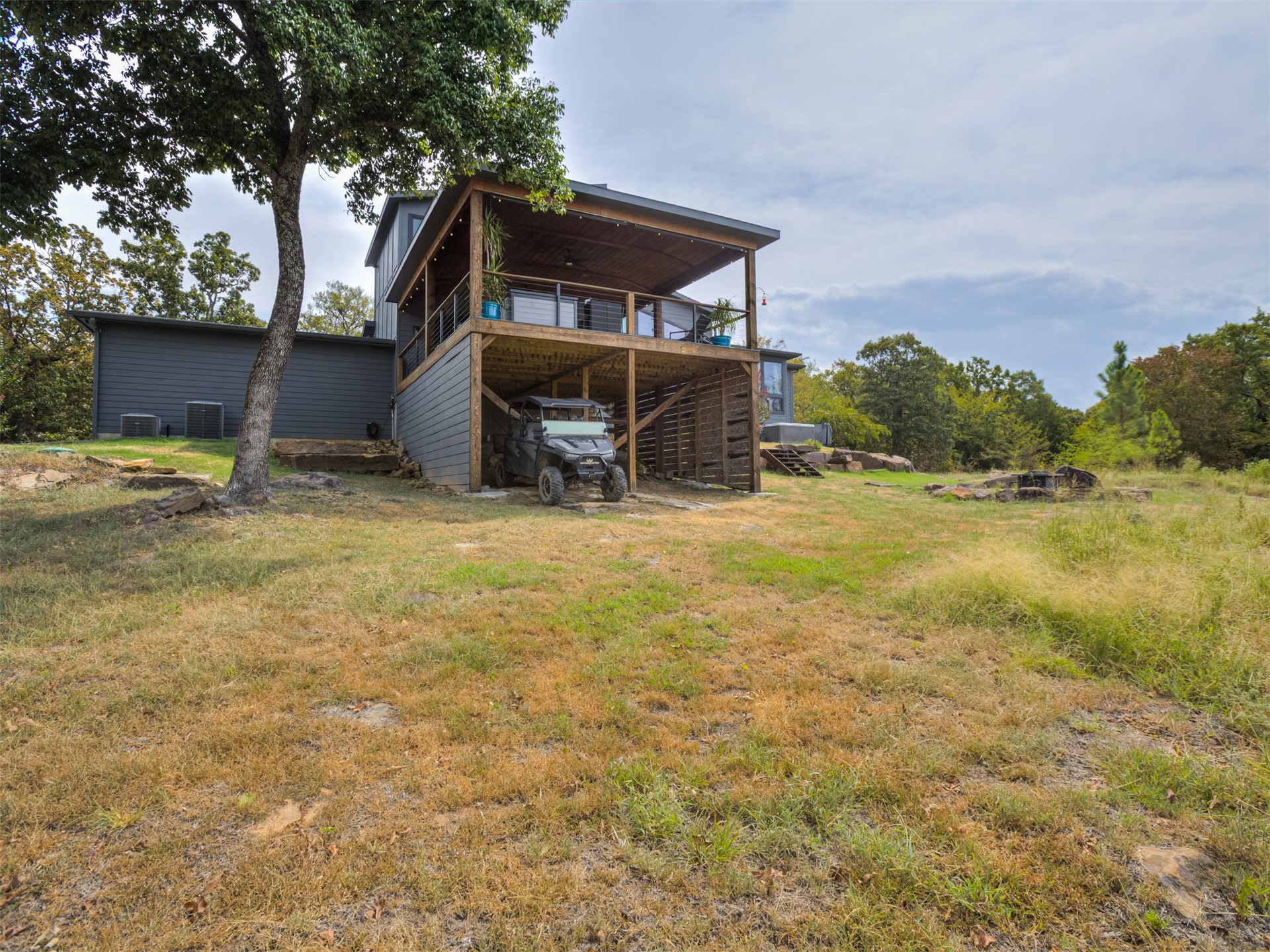 1073 Hidden Ridge Road Stigler, OK 74462 - Photo 49 of 56 Two-story structure with a covered upper-level deck, lower-level covered parking, and dark gray siding
