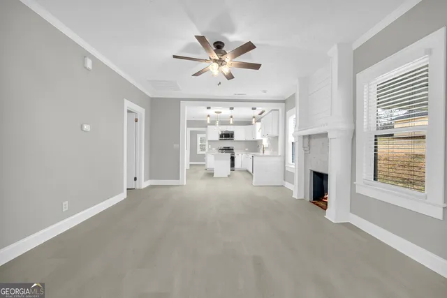 a view of a livingroom with a fireplace a ceiling fan and windows