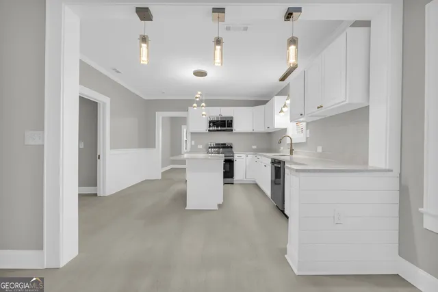 a kitchen with kitchen island granite countertop a white center island a sink stainless steel appliances and cabinets