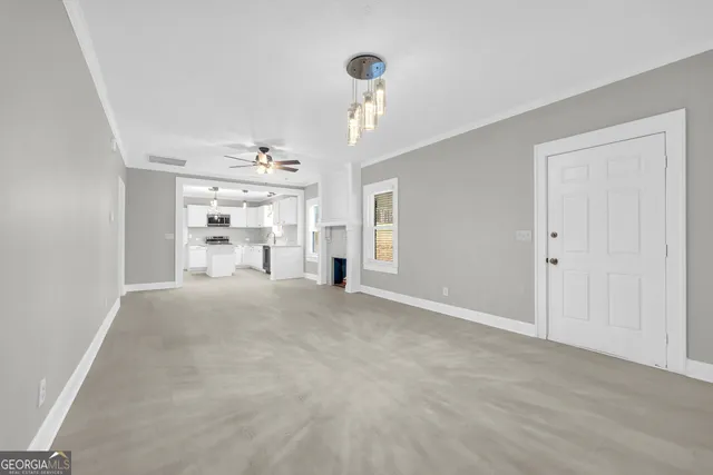 a view of an empty room and a kitchen