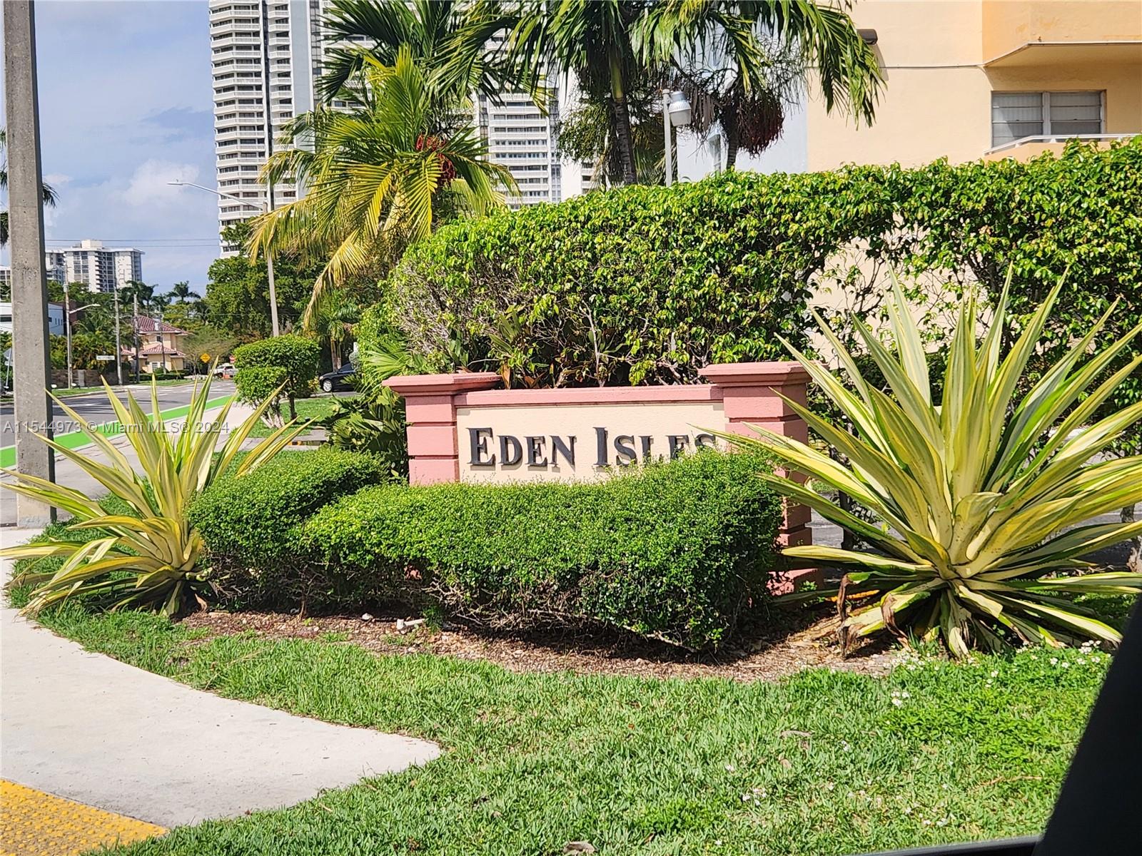 a view of a sign in a yard with palm trees