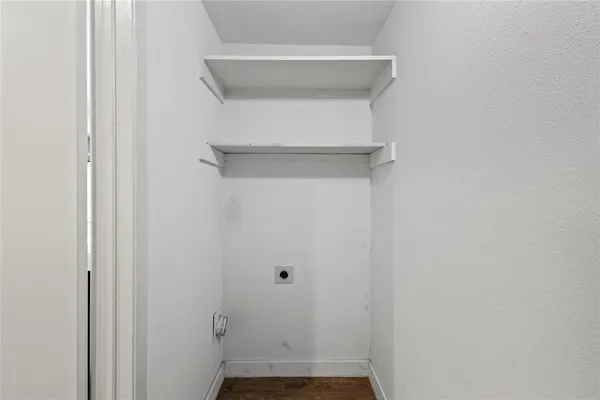 a view of an empty room with wooden floor fireplace and a window