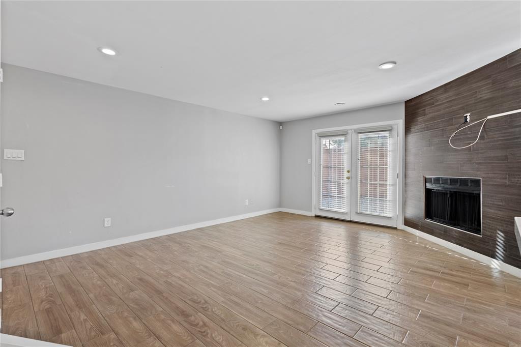 4371 Madera Road, Unit 4 Irving, TX 75038 - Photo 17 of 23 Unfurnished living room with a large fireplace, light hardwood / wood-style flooring, and french doors