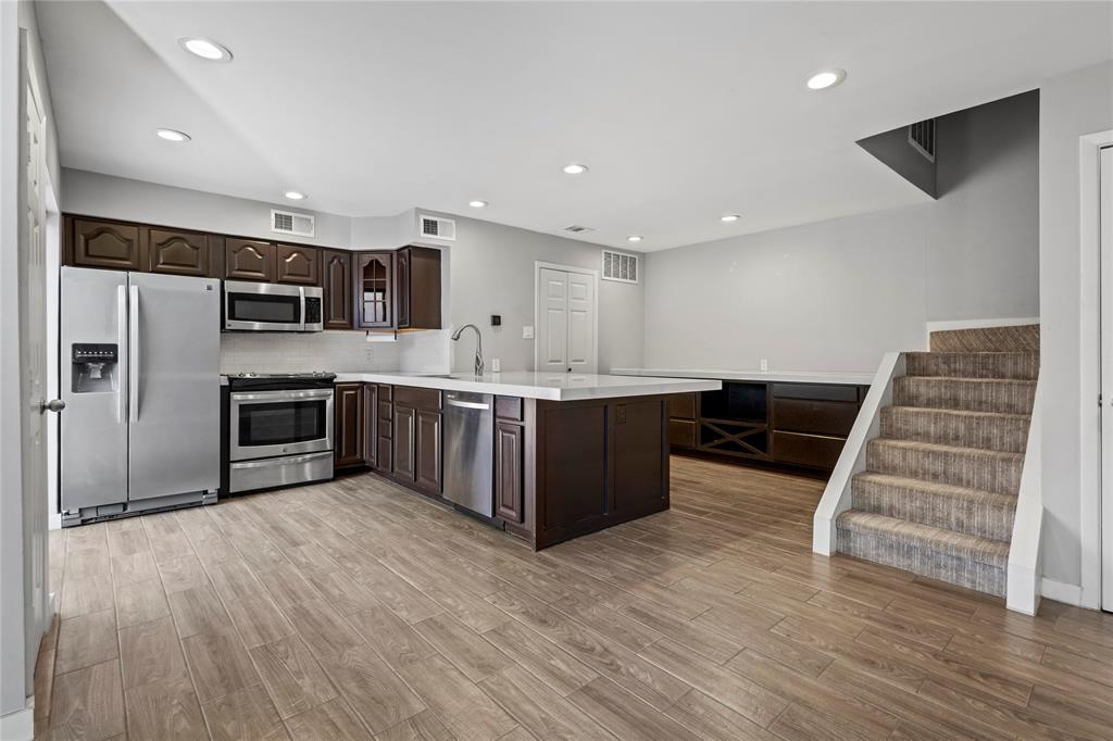 4371 Madera Road, Unit 4 Irving, TX 75038 - Photo 18 of 23 Kitchen with kitchen peninsula, light hardwood / wood-style flooring, dark brown cabinets, appliances with stainless steel finishes, and backsplash